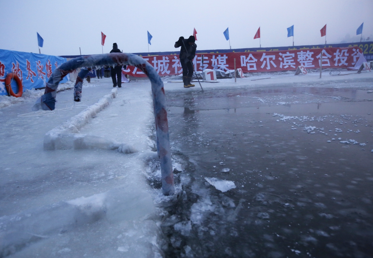 A worker breaks ice on a pool carved into the thick ice covering the Songhua River in China. A worker breaks ice on a pool carved into the thick ice covering the Songhua River in China.
