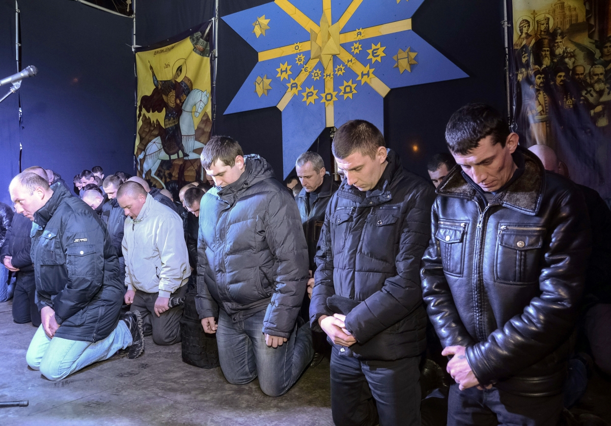 Local riot police kneel as they apologize to Lviv residents for taking part in an operation against anti-government protesters in Kiev