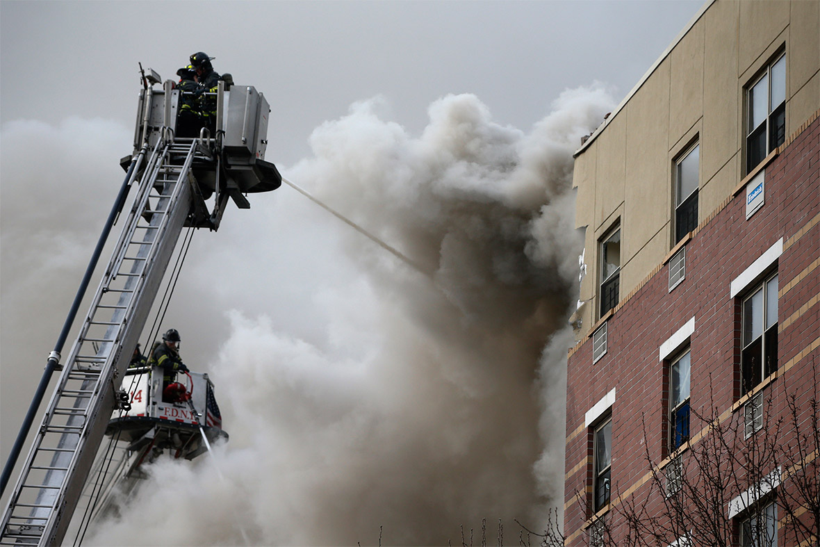 Firefighters try to extinguish a fire at the site of a building collapse in Harlem