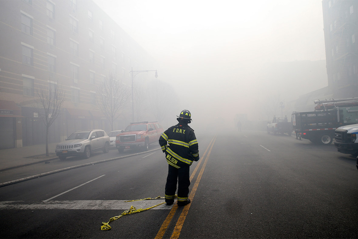 A firefighter is wreathed in smoke and dust on East 116th street