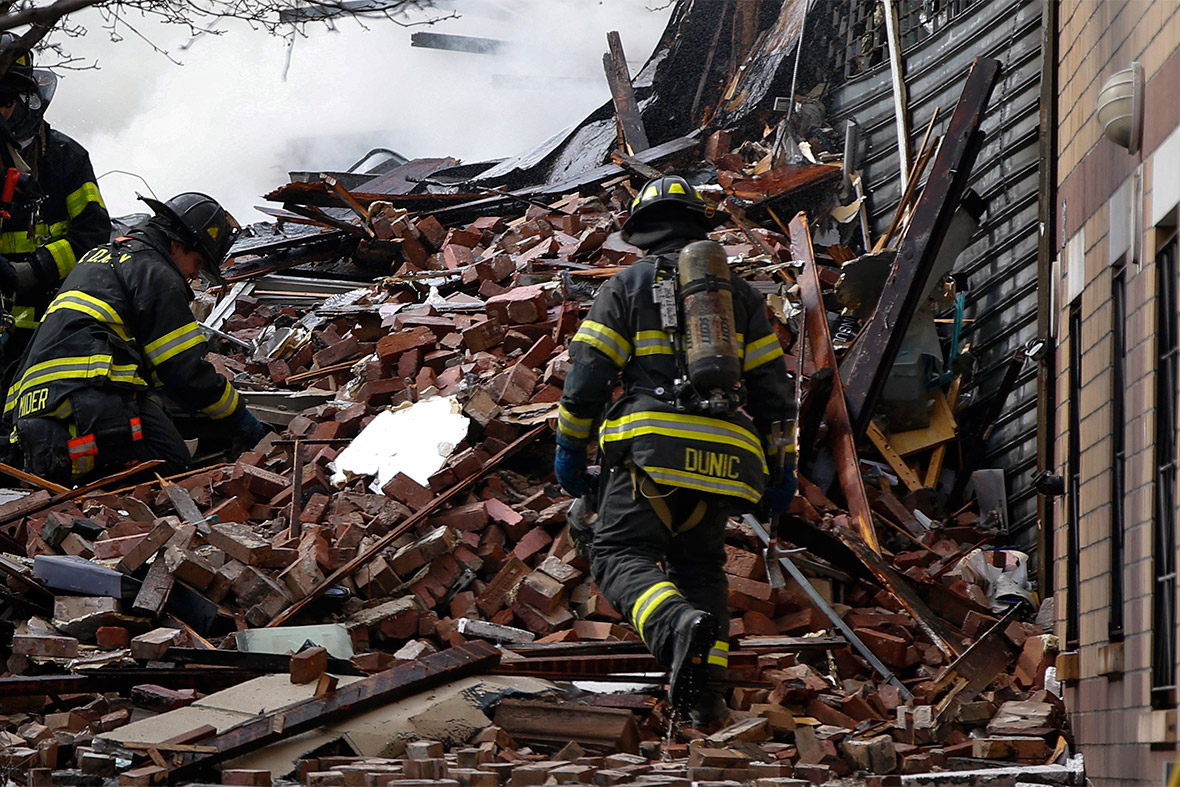 Firefighters go through debris and rubble at the site of a building collapse and fire in Harlem