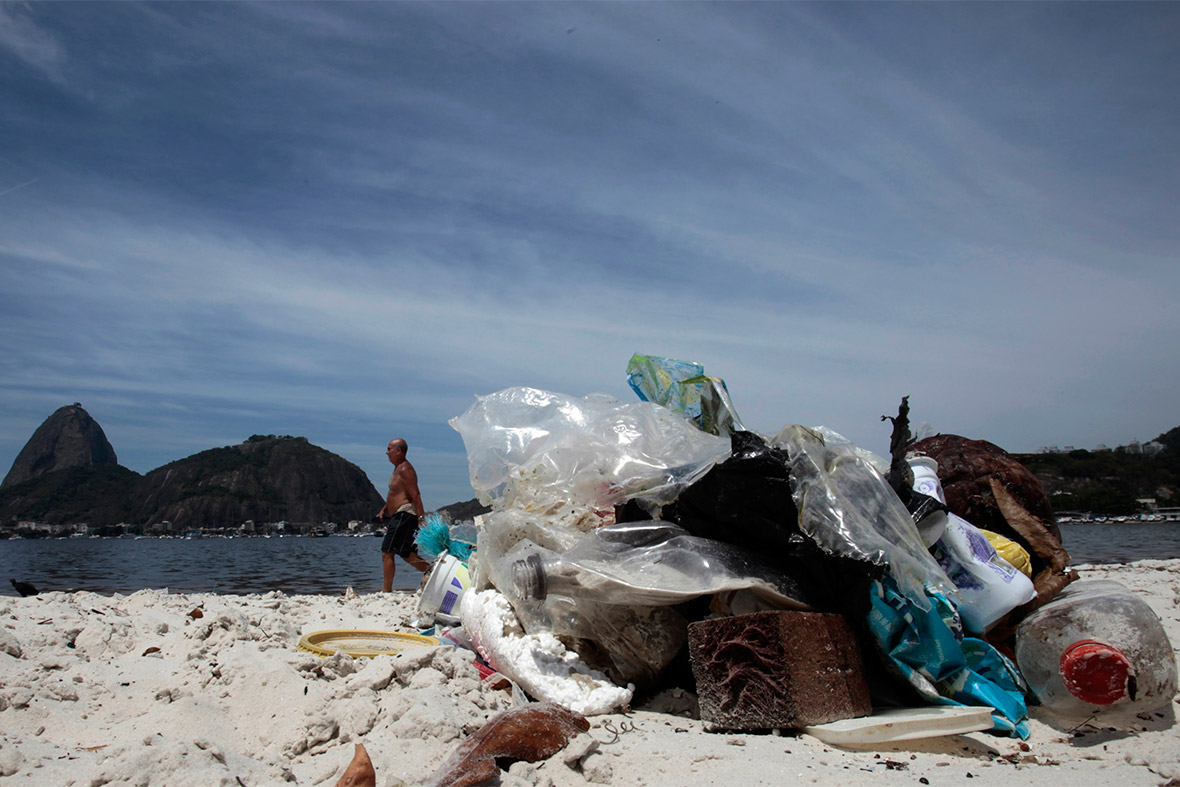 A man walks past rubbish on Botafogo beach, with Sugar Loaf Mountain in the background rio ruibbish