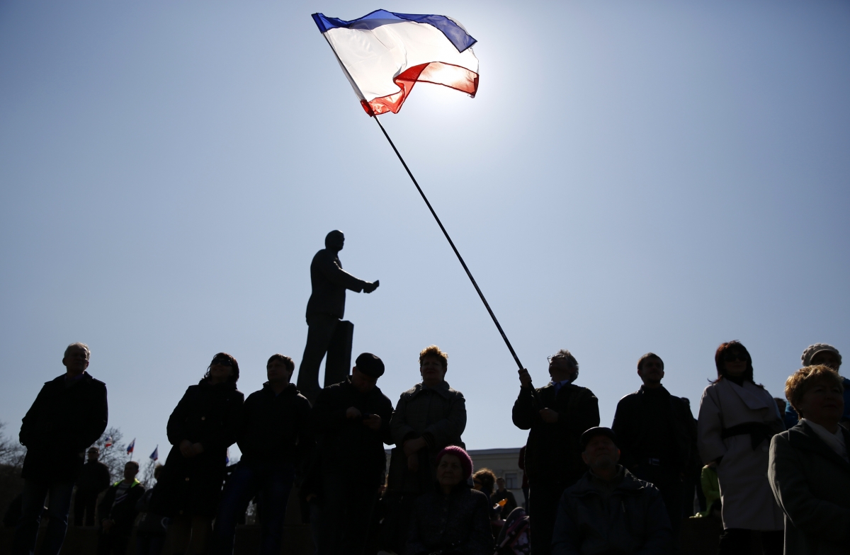 A man holds a Crimean flag during a pro-Russian rally on the eve of a referendum in Lenin Square in Simferopol, 15 March 2014. Ukraine's acting president Oleksandr Turchynov accused A man holds a Crimean flag