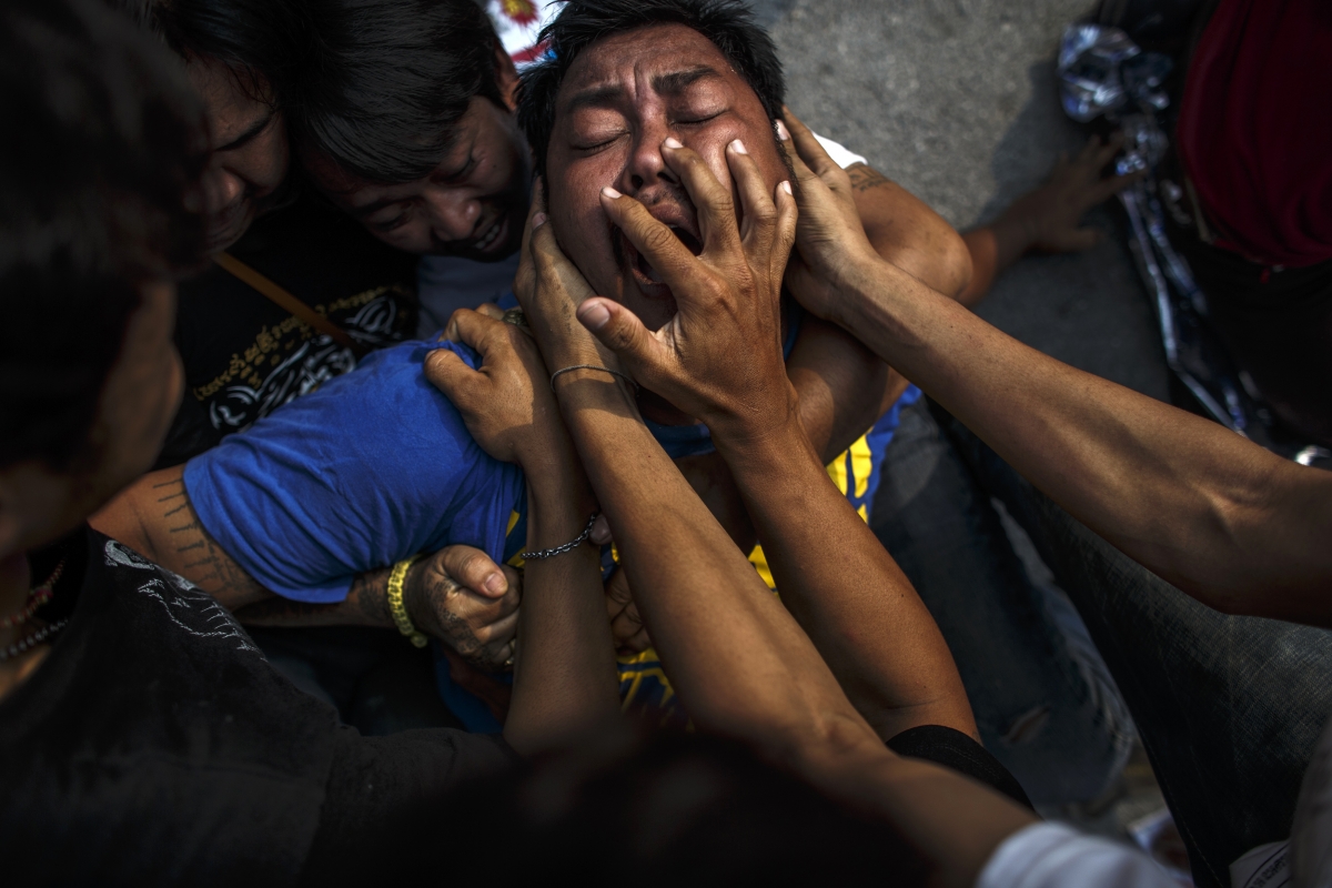 A devotee in a state of trance is calmed by volunteers during the annual Magic Tattoo Festival at Wat Bang Phra in Nakhon Prathom province, 15 March 2014. Believers from across Thailand travel to the monastery to have their bodies adorned with tattoos and to pay their respects to the temple's master tattooist devotee