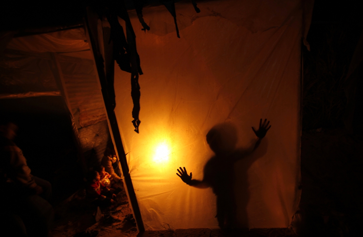 A Palestinian family sits inside their makeshift house during power cuts in Khan Younis in the southern Gaza Strip, 15 March 2014. The Gaza Strip's sole power station stopped generating electricity on Saturday, causing blackouts throughout the territory after it ran out of fuel, officials said Gaza