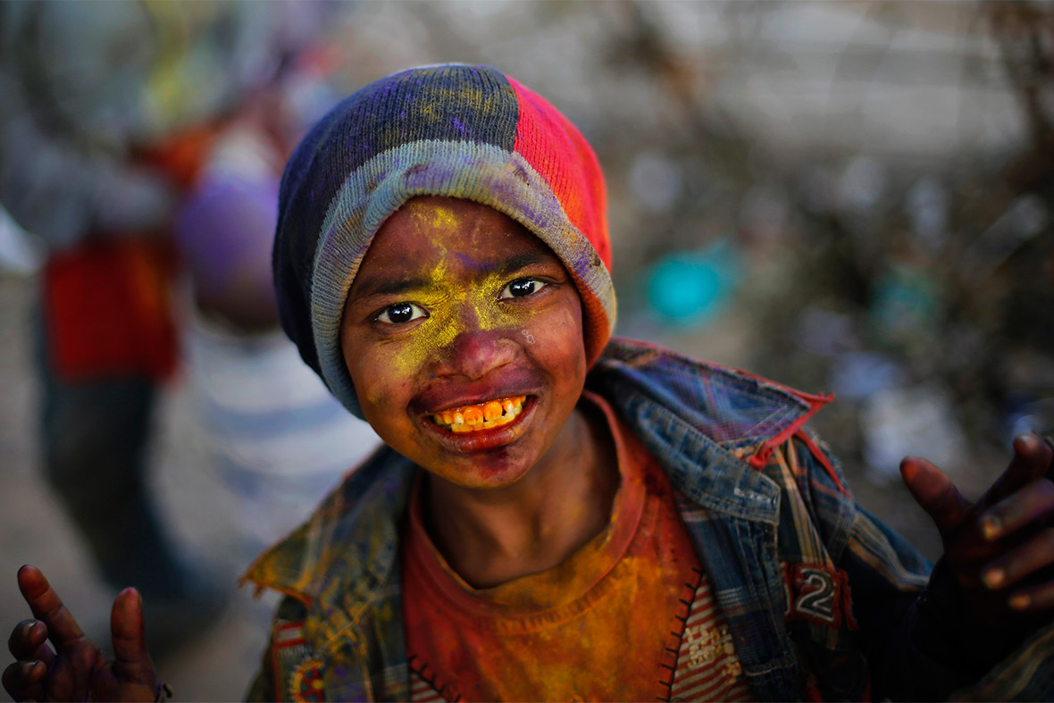 A boy covered in coloured powder smiles in New Delhi