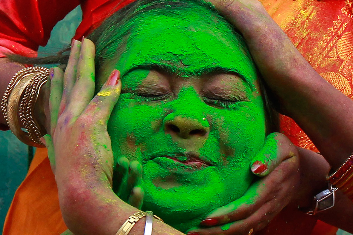 A student of Rabindra Bharati University in Kolkata reacts as her fellow students apply coloured powder to her face