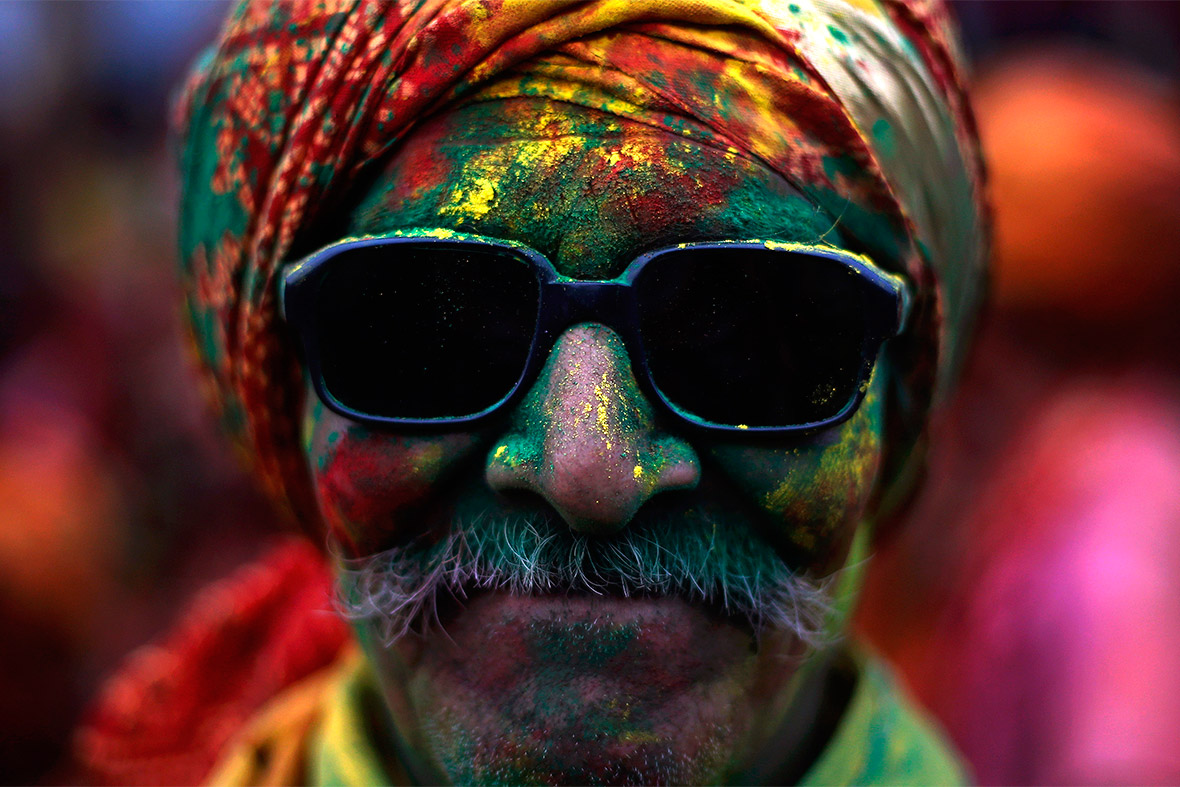 A man daubed in coloured powder poses for a picture at a temple in Nandgaon, in the northern Indian state of Uttar Pradesh