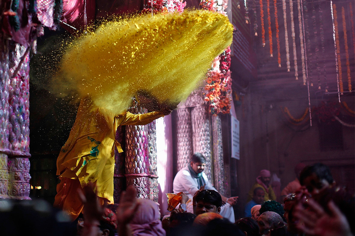 A Hindu priest throws coloured powder at devotees at Bankey Bihari temple in Vrindavan