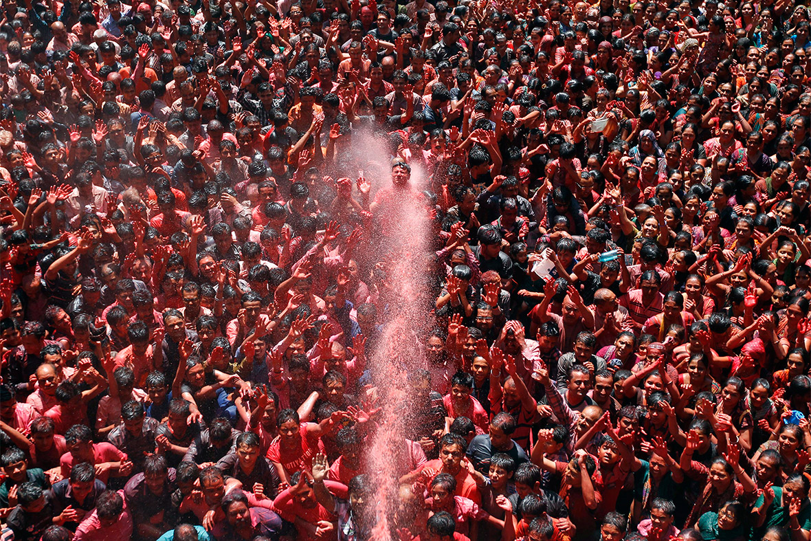 Hindu devotees raise their hands as they are sprayed with colour outside a temple in Ahmedabad