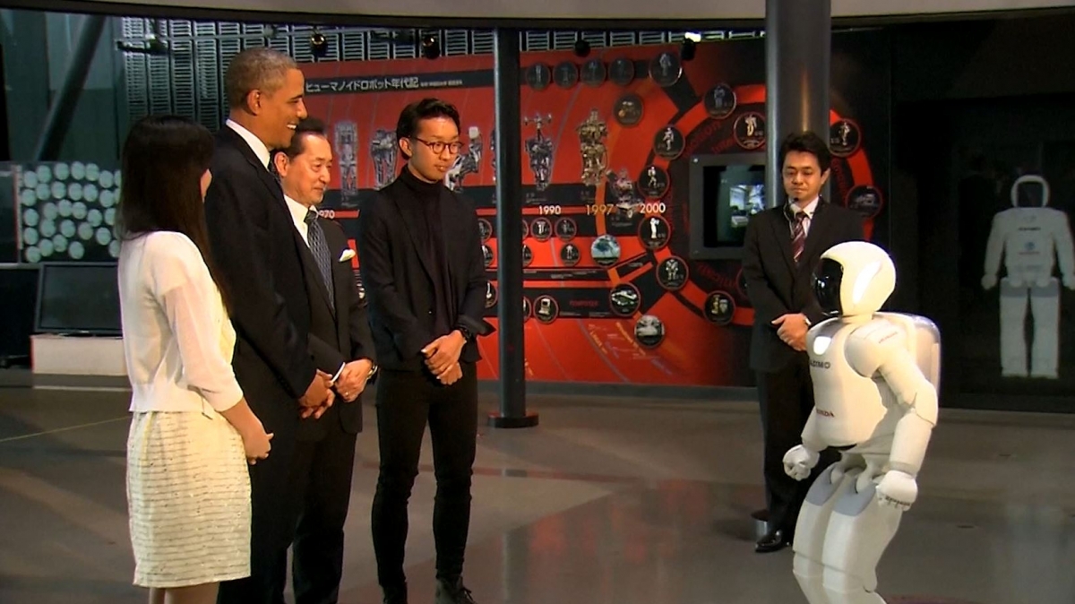 President Obama plays football with a humanoid robot while touring Japan