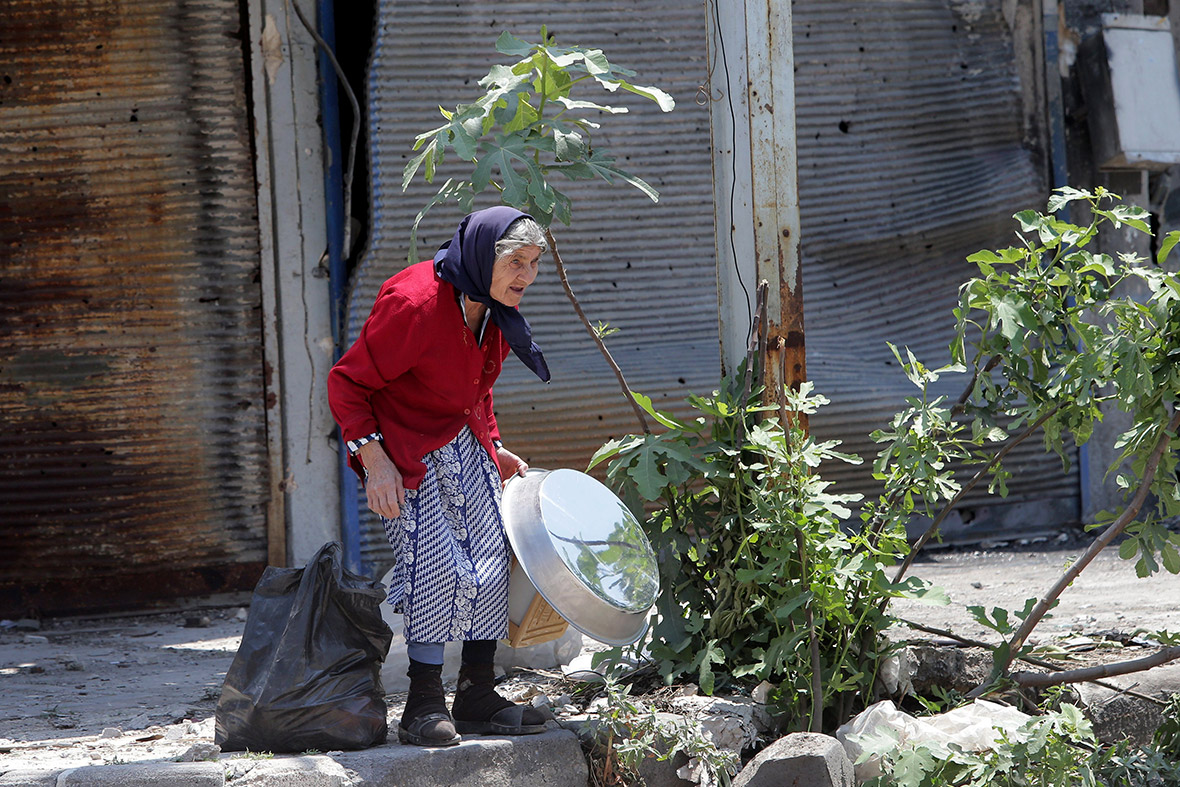 A resident of the Old City of Homs carries belongings she retrieved from her destroyed home