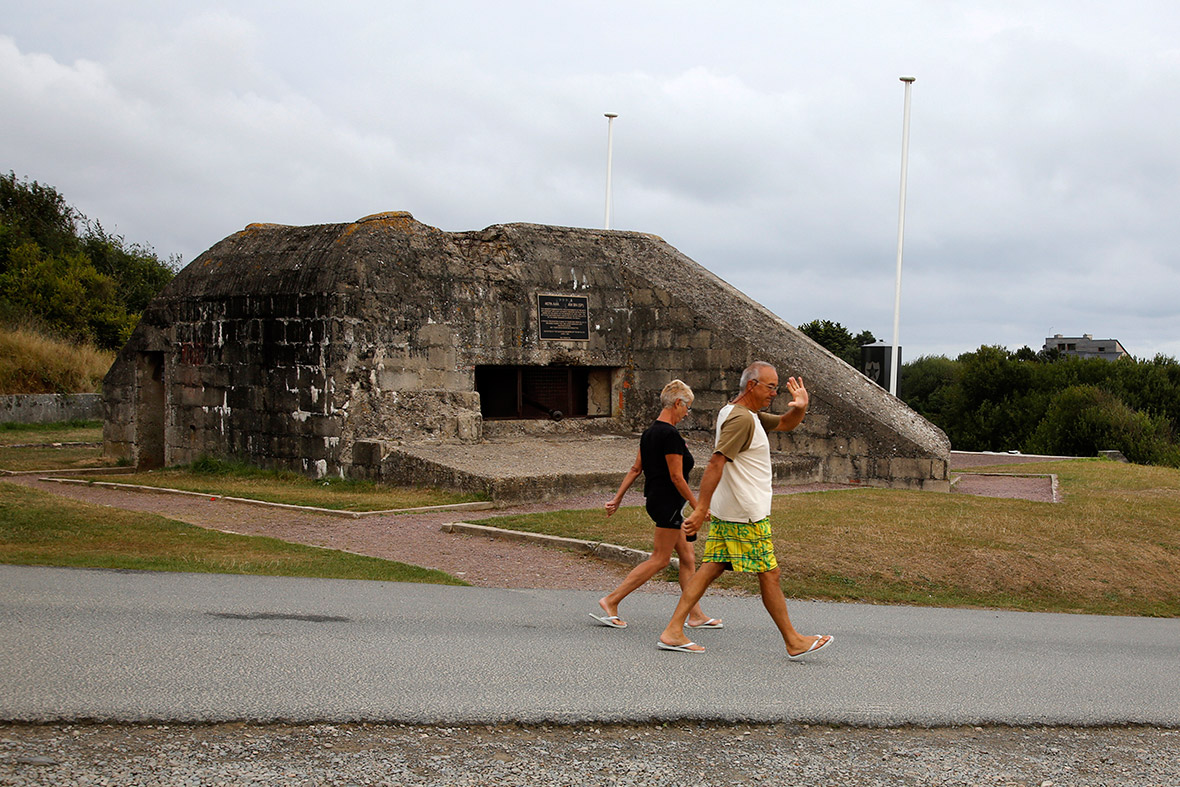 Tourists walk past a former German bunker overlooking the D-Day landing zone on Omaha Beach near Saint Laurent sur Mer, France