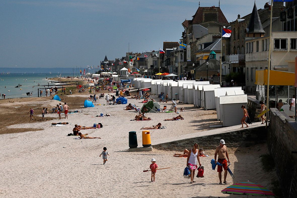 Os turistas apreciam a luz do sol sobre a antiga zona de aterragem Juno Beach D-Day, onde as forças canadenses desembarcaram em Saint-Aubin-sur-Mer, França