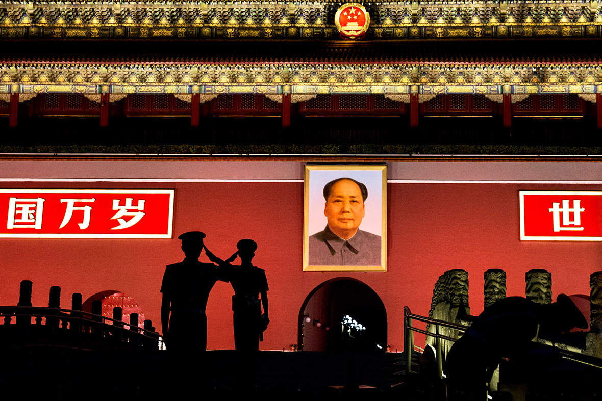 Chinese Paramilitary police officers salute each other as they stand guard below a portrait of the late leader Mao Tse-tung on Tiananmen Square