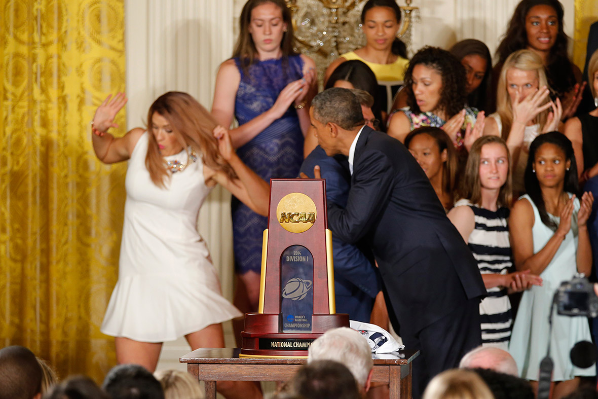 Stefanie Dolson falls off the stage as US President Barack Obama hugs University of Connecticut women's basketball coach Geno Auriemma during a ceremony honouring the NCAA basketball champions in the East Room of the White House in Washington.