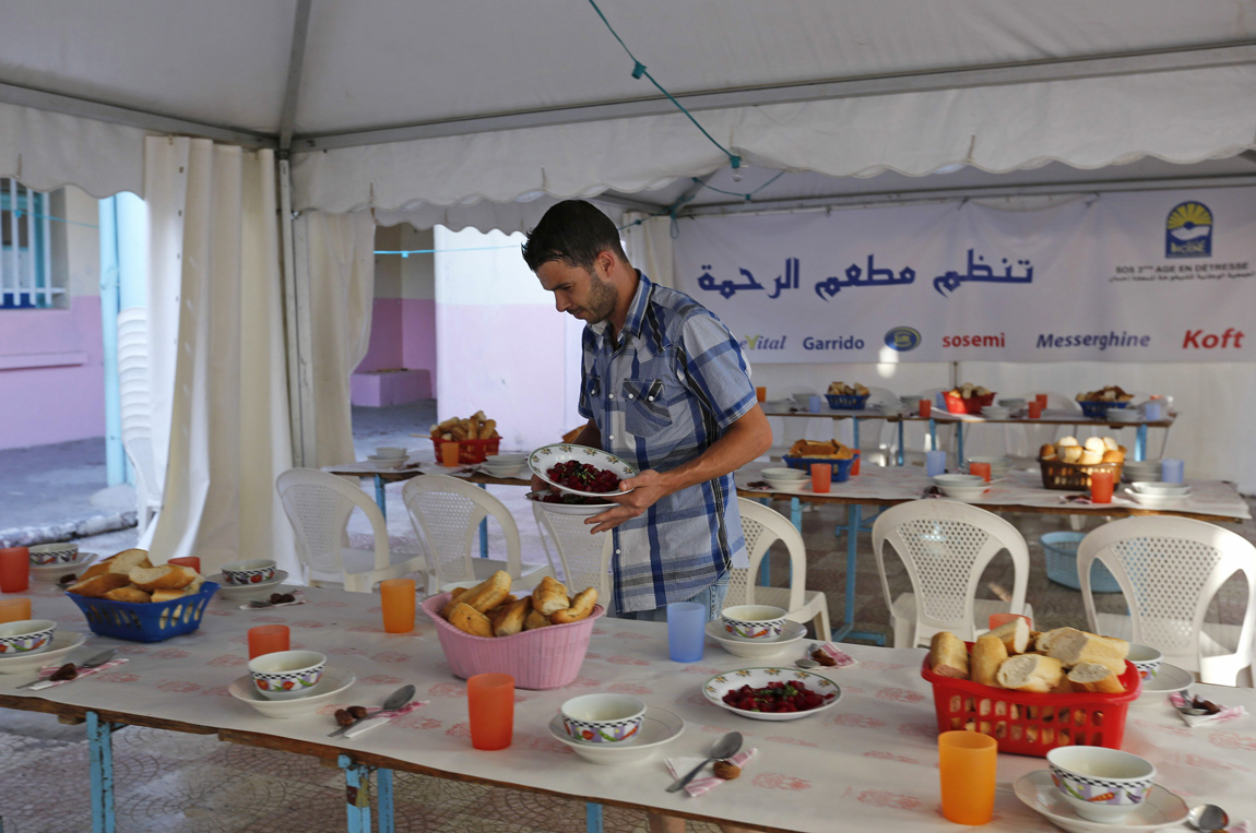 Volunteers set up tables before breaking fast at a charity food distribution centre by humanitarian association Ihcene on the outskirts of Algiers Volunteers at a charity prepare food for Iftar in Algeria