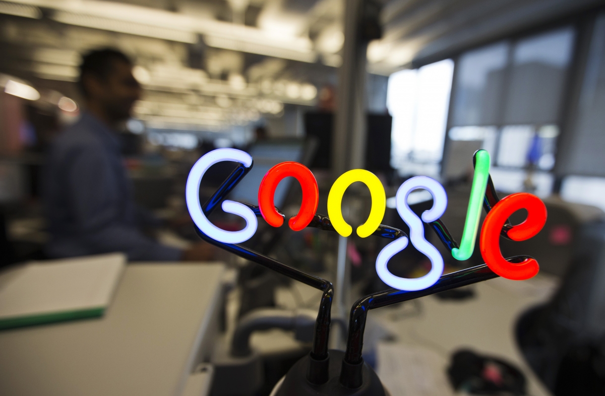 A neon Google logo is seen as employees work Google neon sign