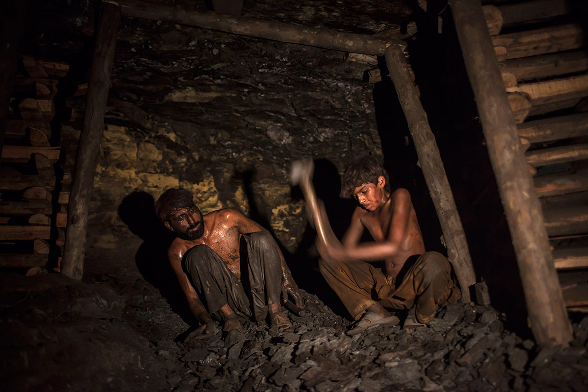 Samiullah, who says he is 14 years old, breaks coal underground in the mine