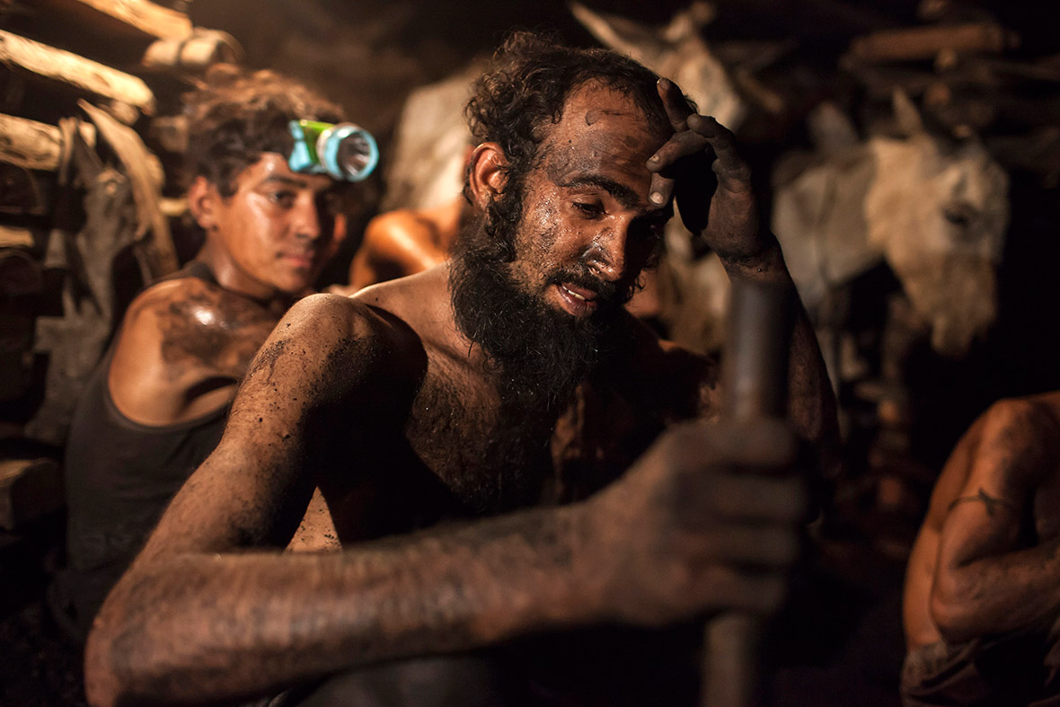A miner wipes sweat from his forehead inside the coal mine