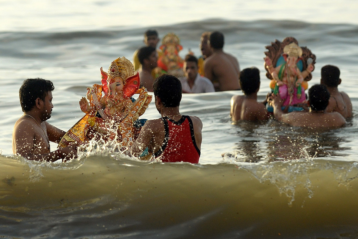 Hindu devotees carry idols of Ganesh into the Arabian Sea at Dadar Chowpatty beach in Mumbai