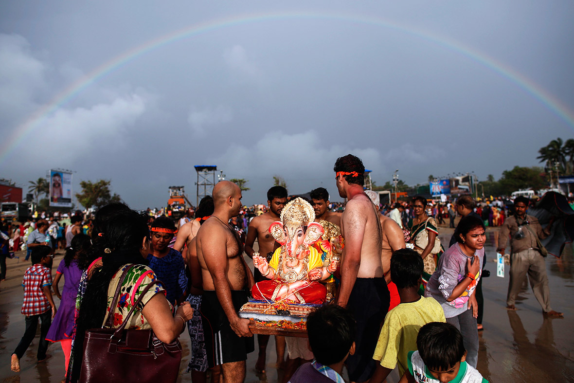 A rainbow is seen as devotees carry a statue of Lord Ganesh, the deity of prosperity, into the Arabian Sea in Mumbai