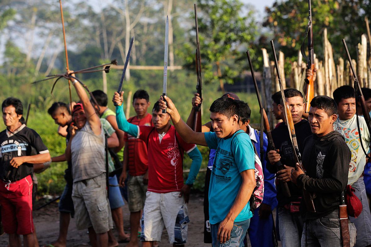 Ka'apor warriors raise their weapons as they leave the village of Waxiguy Renda to look for loggers in the Amazon