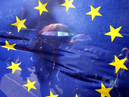 People walk behind the European Union's flag