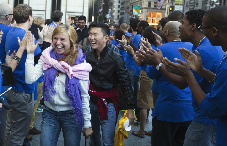 Customers laugh while greeted by Apple employees as they arrive to purchase the Apple iPhone 5 phone at the Apple Store on 5th Avenue in New York