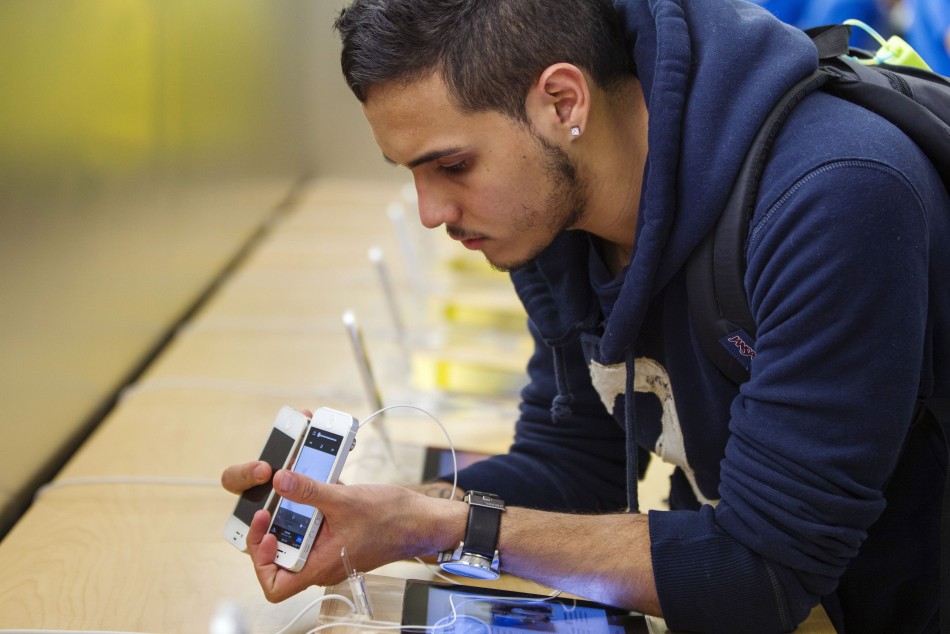 A customer compares his older iPhone to an Apple's iPhone 5 phone after purchasing one at the Apple Store on 5th Avenue in New York