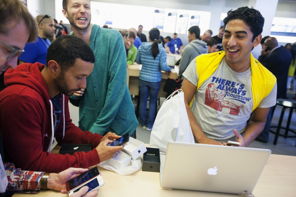 Customers laugh with each other after purchasing their Apple iPhone 5 phones inside the Apple Store on 5th Avenue in New York