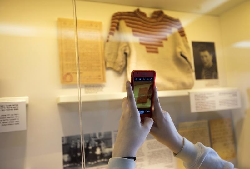 Grand-daughter of Holocaust survivor Gucia Teiblum, takes a photograph of a sweater knitted by her grandmother at a Nazi concentration camp, during the opening of a new display at the Yad Vashem Holocaust History Museum in Jerusalem January 27, 2013.