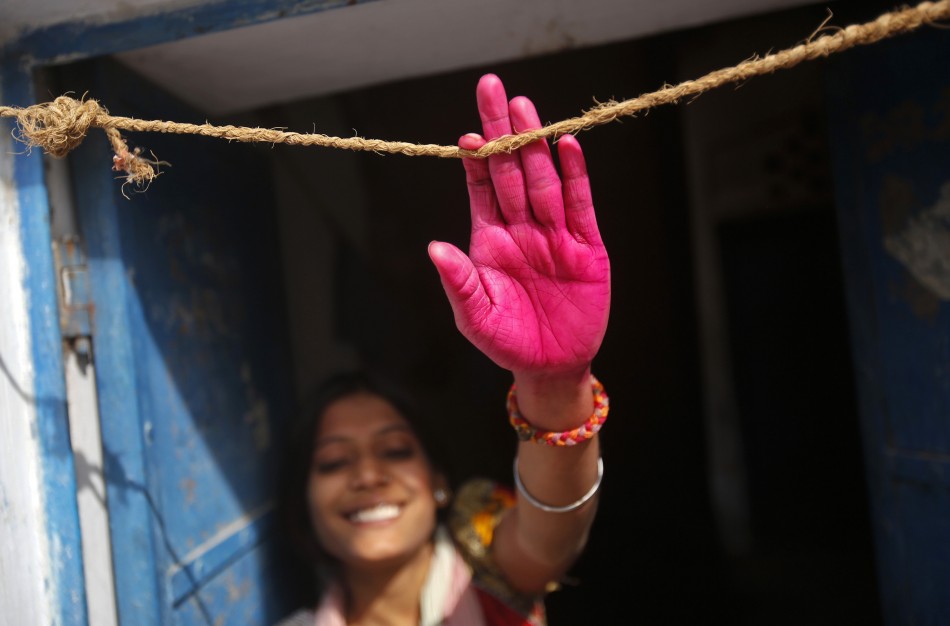 A woman with her hand stained by coloured water poses for a picture during Holi celebrations in a lane near the Bankey Bihari temple in Vrindavan in the northern Indian state of Uttar Pradesh March 26, 2013. Holi, also known as the Festival of Colours, heralds the beginning of spring and is celebrated all over India.