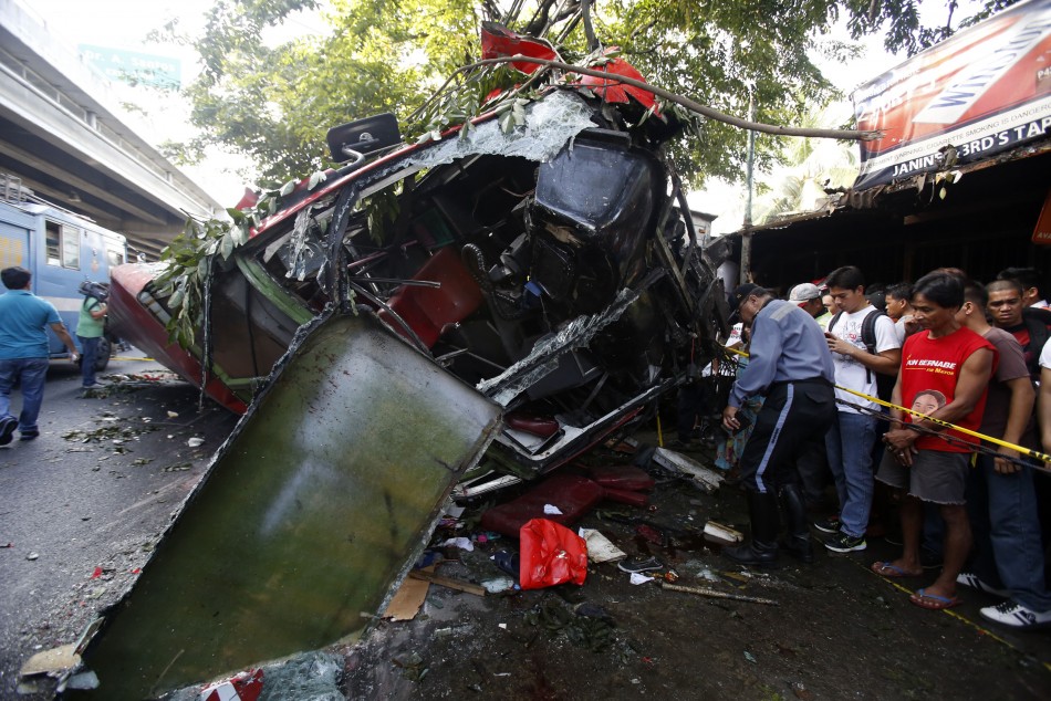 A policeman searches for personal belongings of passengers after a bus fell off an elevated expressway and crashed into a van below in Taguig city, south of Manila