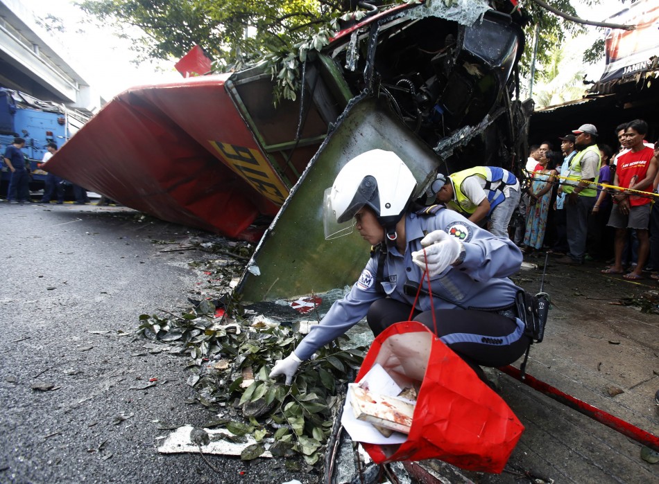 A policewoman searches for personal belongings of passengers after a bus fell off an elevated expressway and crashed into a van below in Taguig city, south of Manila