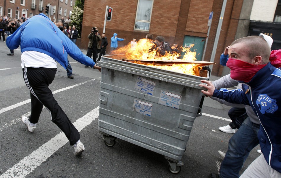 Youths push a burning rubbish bin towards riot police during disturbances at the start of the Queen039s visit to Ireland.