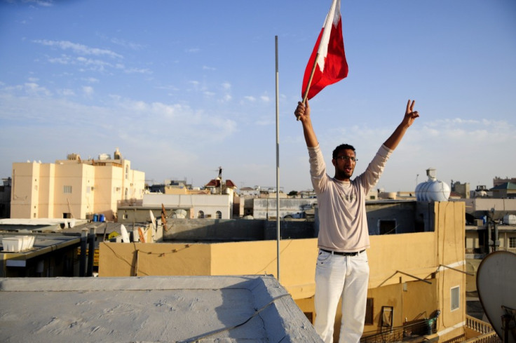 A man holds a flag as he protests against the crackdowns from a rooftop in the village of Sanabis