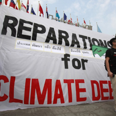 Activists from JSAPMDD shout slogan near a banner during a demonstration in front of the United Nations building in