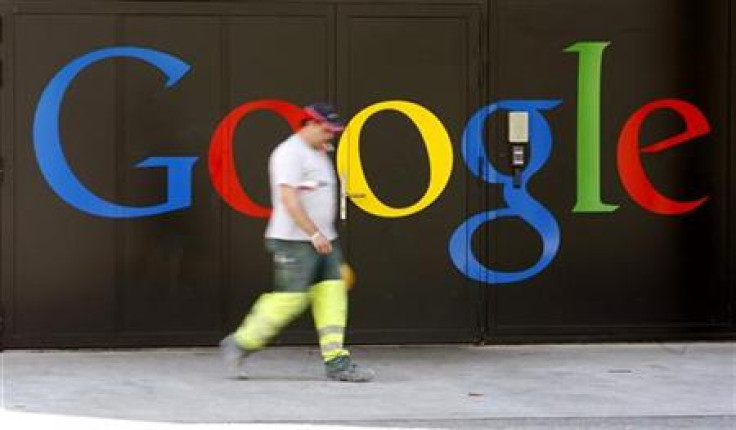 A construction worker walks past a logo next to the main entrance of the Google building
