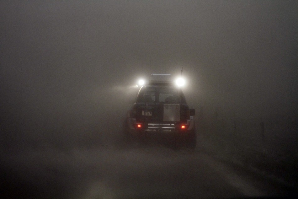 A car is seen through a cloud of ash at the Geirland farm near Kirkjubaejarklaustur.