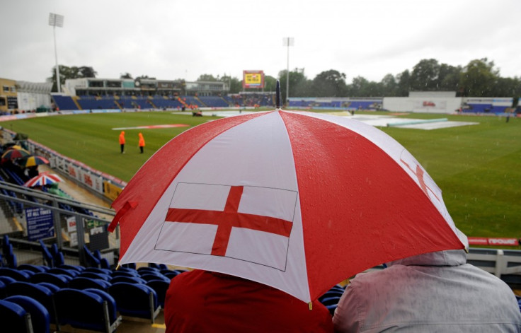 A fan waits under an umbrella as the start of the first cricket test match between England and Sri Lanka is delayed by rain at the Swalec Stadium at Cardiff.