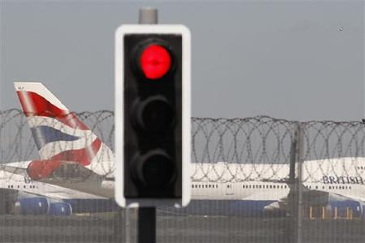 A British Airways aircraft manoeuvres behind a red traffic light at Heathrow Airport