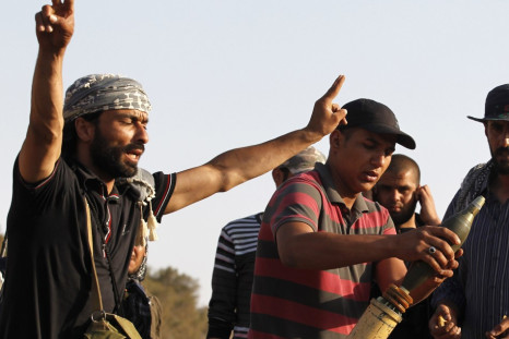 A Libyan fighter shouts while his comjrade loads a mortar at Misrata's western front line