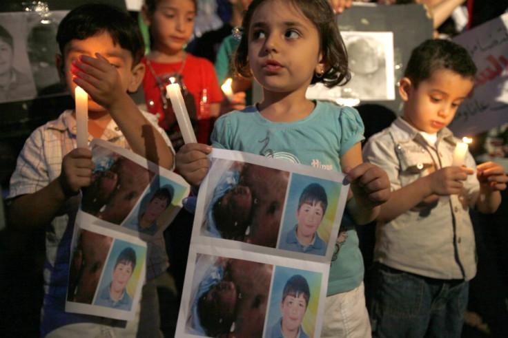 Syrian children carry pictures of Syrian boy Hamza al-Khatib and hold candles during a protest in front of the United Nations building in Beirut