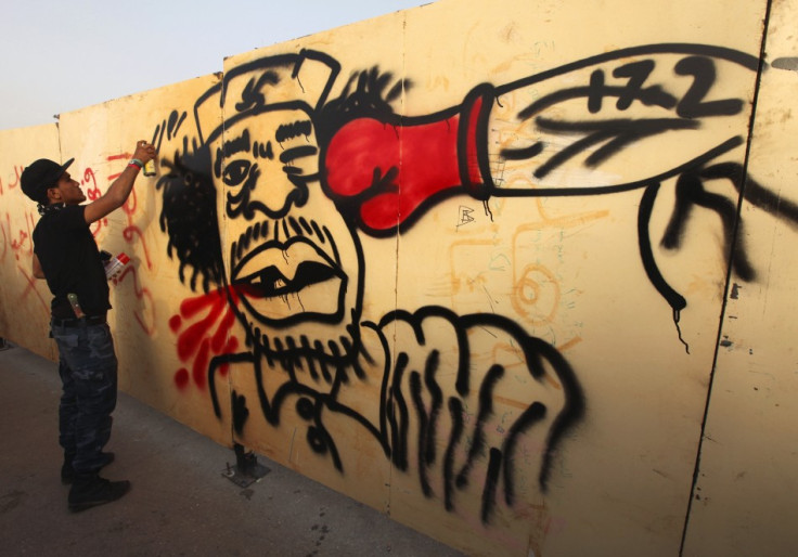 A painter paints a caricature of Libyan leader Muammar Gaddafi in Benghazi