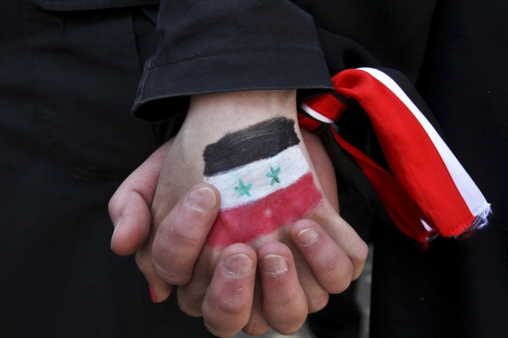 Syrians living in Jordan clasp hands during a protest against Syria's President Bashar Al-Assad outside the U.N. office in Amman