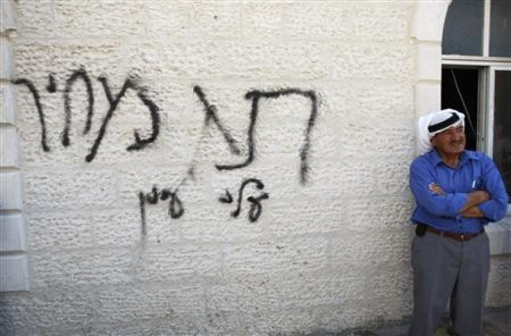 A Palestinian man stands next to Hebrew graffiti