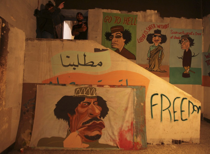 People stand next to caricatures of Muammar Gaddafi in Benghazi