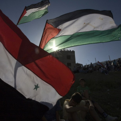 Residents of Majdal Shams hold flags on the border between Israel and Syria in the Golan Heights