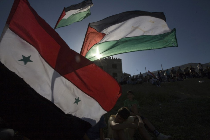 Residents of Majdal Shams hold flags on the border between Israel and Syria in the Golan Heights